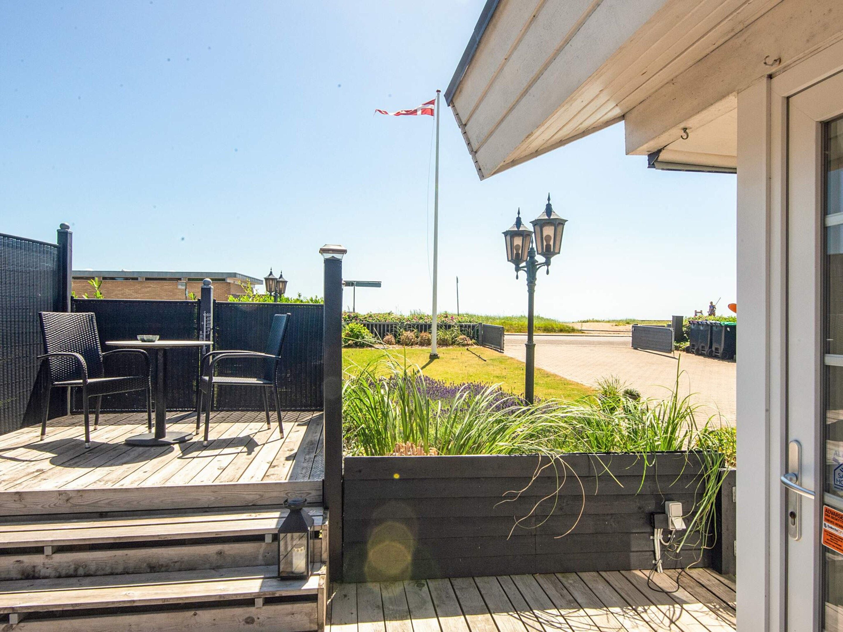 An outdoor patio with a table and chairs, a flag, and a street view in the background.