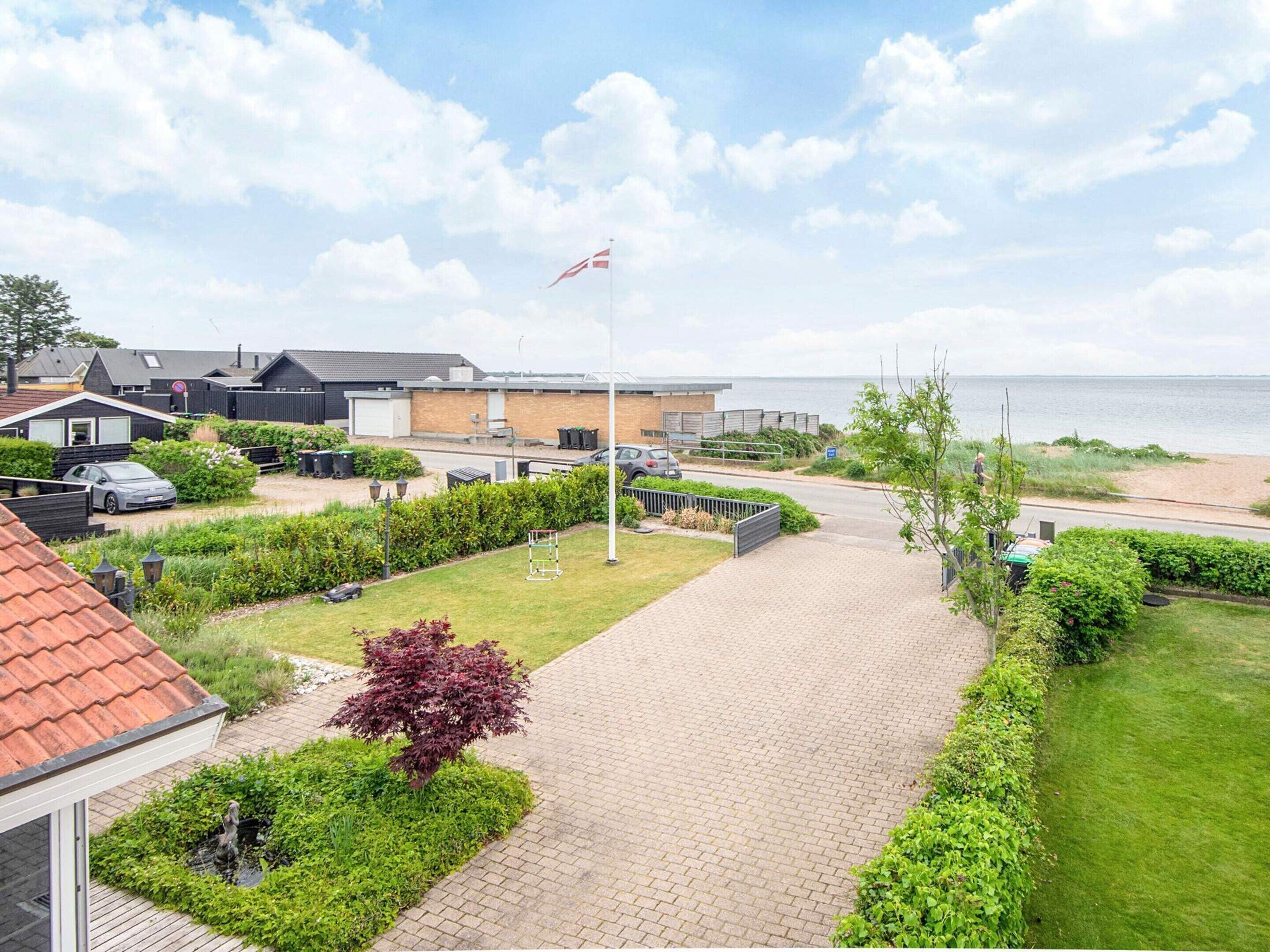 A residential area with a paved walkway, a flag, and a view of the sea.