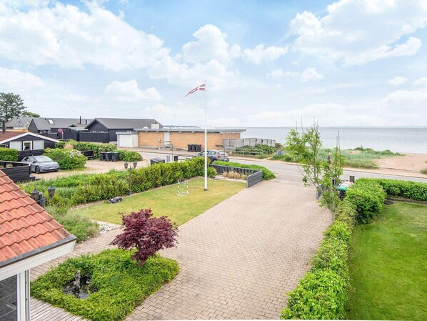 A residential area with a paved walkway, a flag, and a view of the sea. - 4 Star Holiday Home in Haderslev (Haderslev)
