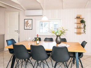 A dining area with a wooden table, black chairs, a vase with flowers, and a framed picture on the wall. - 4 Star Holiday Home in Haderslev (Haderslev)