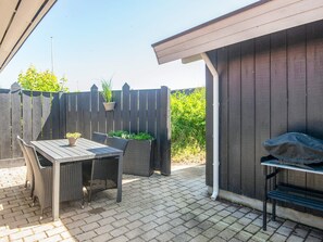 An outdoor patio with a table and chairs, a grill, and a wooden fence. - 4 Star Holiday Home in Haderslev (Haderslev)