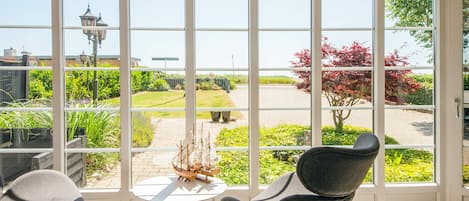 A room with large windows, a round table, two chairs, and a ship model.