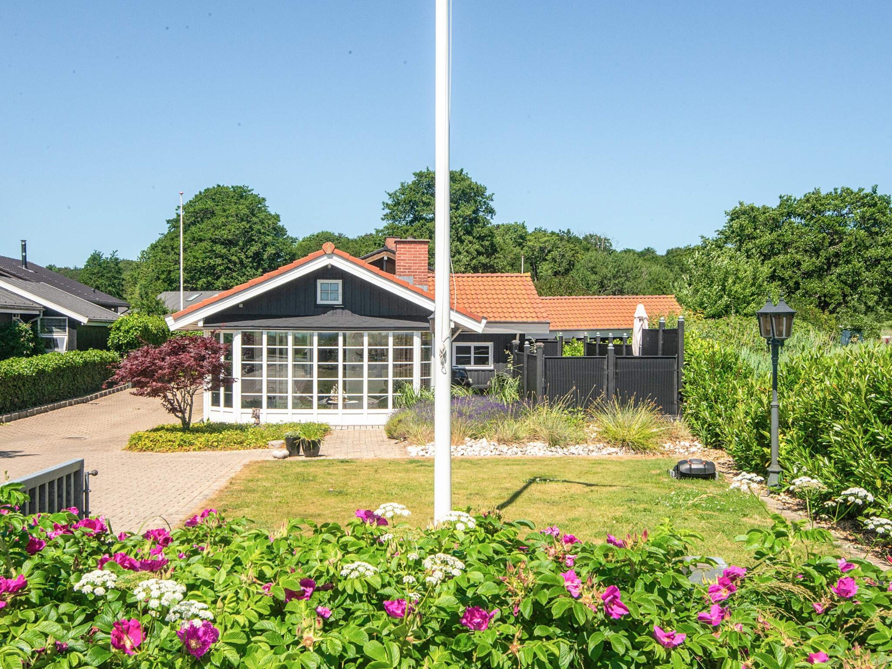 A residential property with a large windowed room, a fenced garden, and a clear sky.