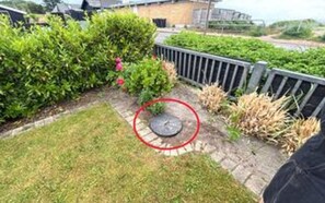 A garden with a paved pathway, a metal fence, and a circular object circled in red. - 4 Star Holiday Home in Haderslev (Haderslev)