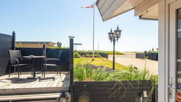 A wooden deck with outdoor seating, a flag, and a street view.