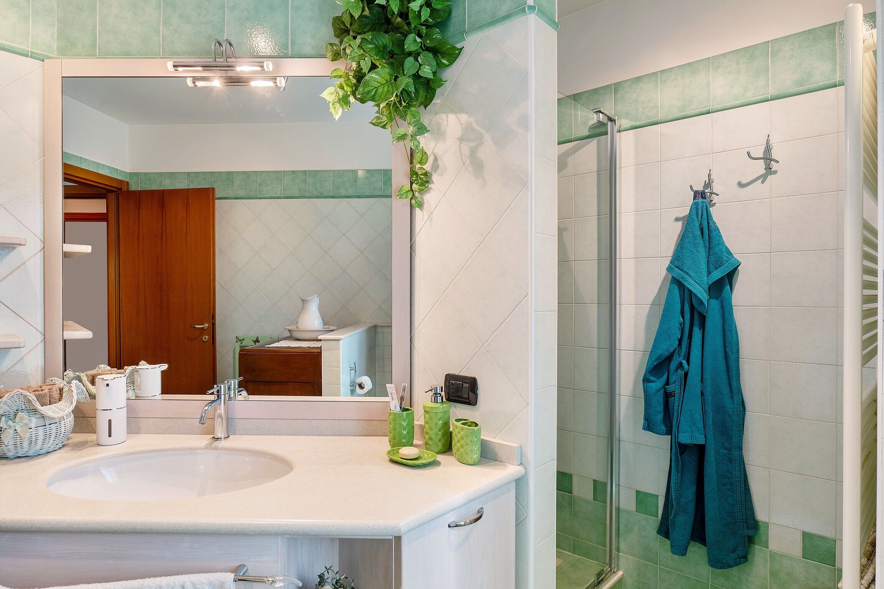 Un baño con un espejo grande, un lavabo, una ducha y un perchero para toallas.