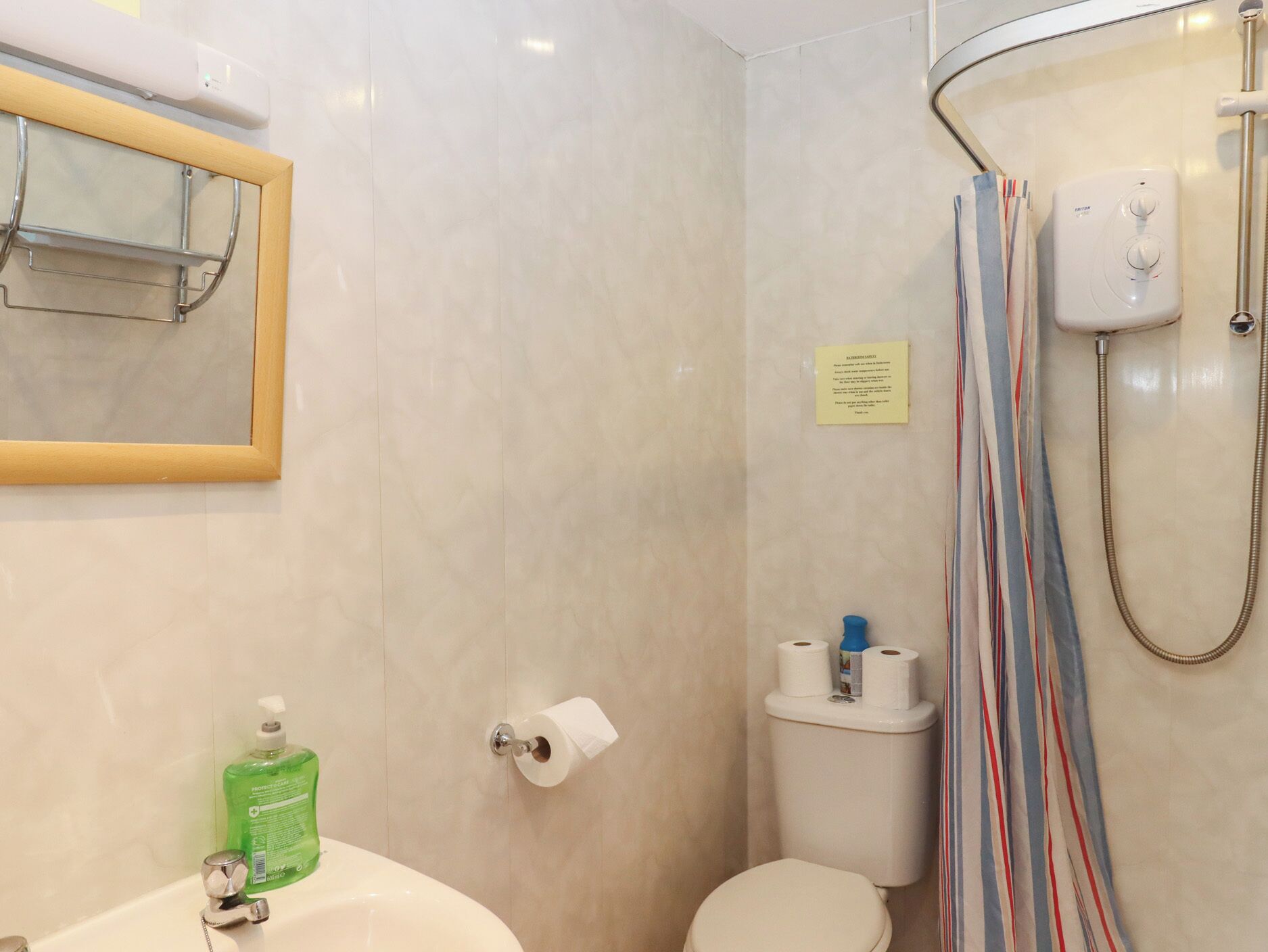 A bathroom with a sink, toilet, shower, and a mirror.