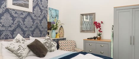 A neatly arranged bedroom with a bed, bedside table, dresser, and wardrobe.
