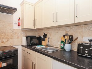 A kitchen with beige cabinets, a black microwave, a stove, and a sink. - Apartment 4 (Torquay)