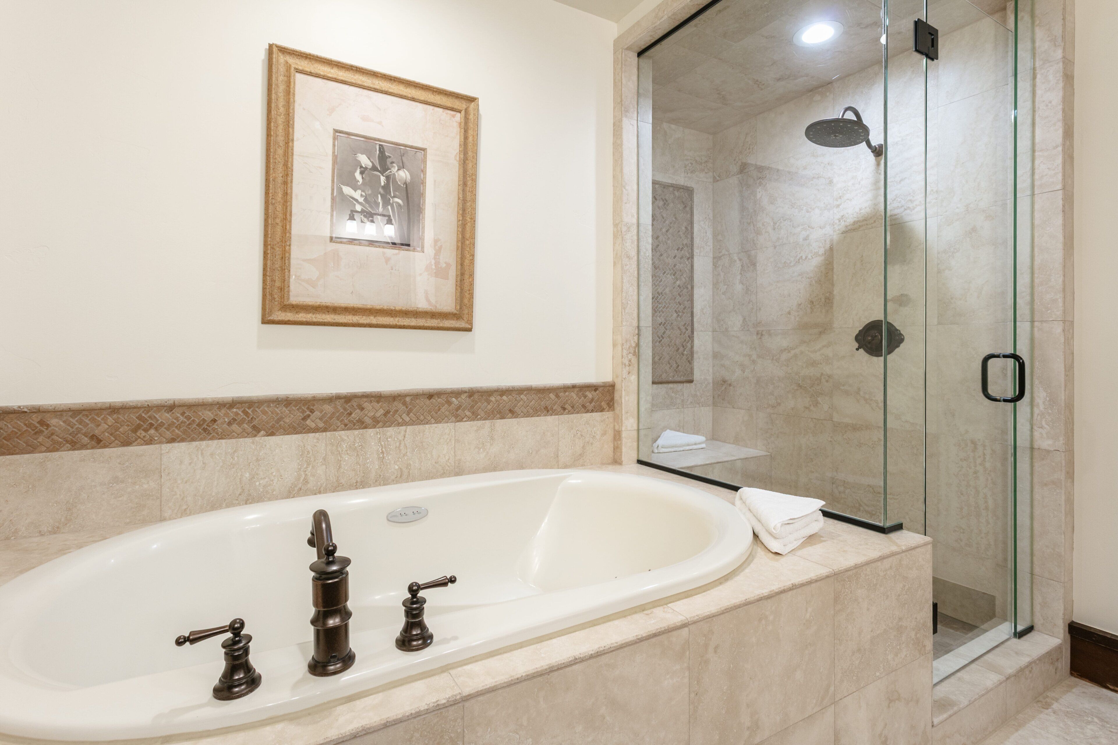 Een badkamer met een bad, een douche en een inlijst foto aan de wand.