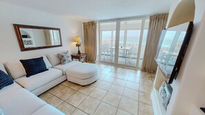 Ein modernes Wohnzimmer mit einer Couch, Hocker und einem großen Fenster mit Blick.