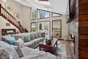 A spacious living room with a large sofa, a coffee table, and a staircase leading to an upper level.