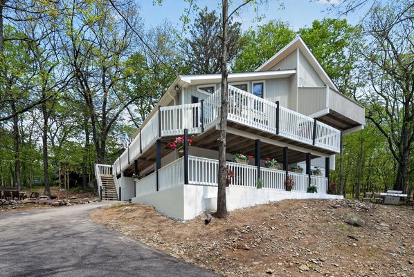 Une maison à deux étages avec un balcon, une véranda et une allée non pavée.