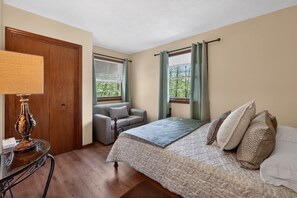 Une chambre à coucher avec un lit, une chaise, une table avec une lampe et une porte.