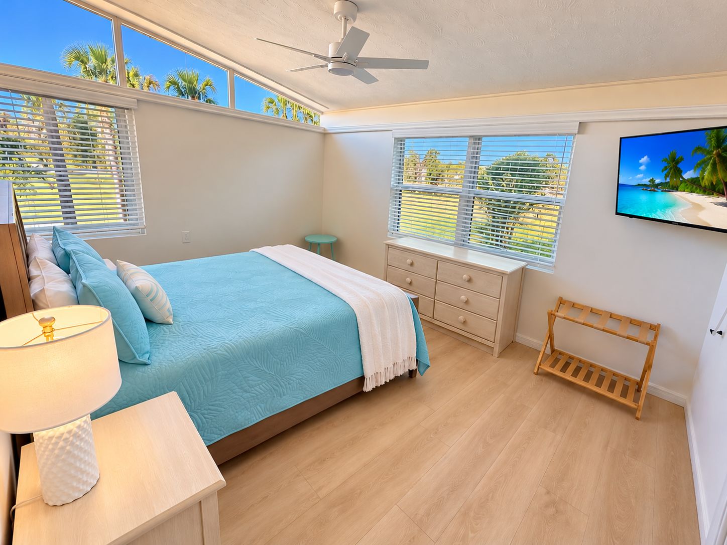 Ein Schlafzimmer mit einem Bett, einem Nachttisch, einer Lampe, einer Kommode, einer Bank und einem Fernseher an der Wand.