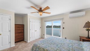 Quarto com cama, ventilador de teto, cômoda, janela com vista e ar condicionado.