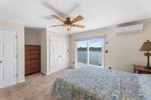 Ein Schlafzimmer mit Bett, Deckenventilator, Kommode, Fenster mit Ausblick und Klimaanlage.