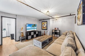 Ein modernes Wohnzimmer mit einer Couch, einem Couchtisch, einem Fernseher und einem Bücherregal.