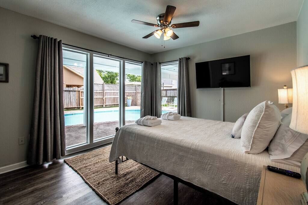 Ein Hotelzimmer mit Bett, Deckenventilator, Fernseher und Blick auf einen Pool.