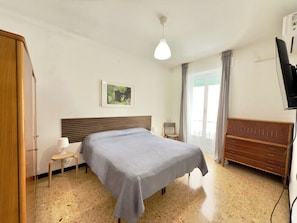 Ein Schlafzimmer mit einem Bett, einem Nachttisch, einer Lampe und einer Holzkommode.