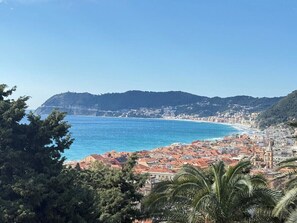 Eine Küstenstadtlandschaft mit Gebäuden, einem Strand und einem Berg im Hintergrund.