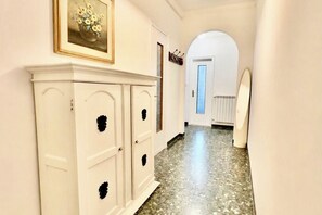 Ein Flur mit einem weißen Schrank, einem gerahmten Bild, einer Tür mit Milchglasfüllung und einem weißen Heizkörper.