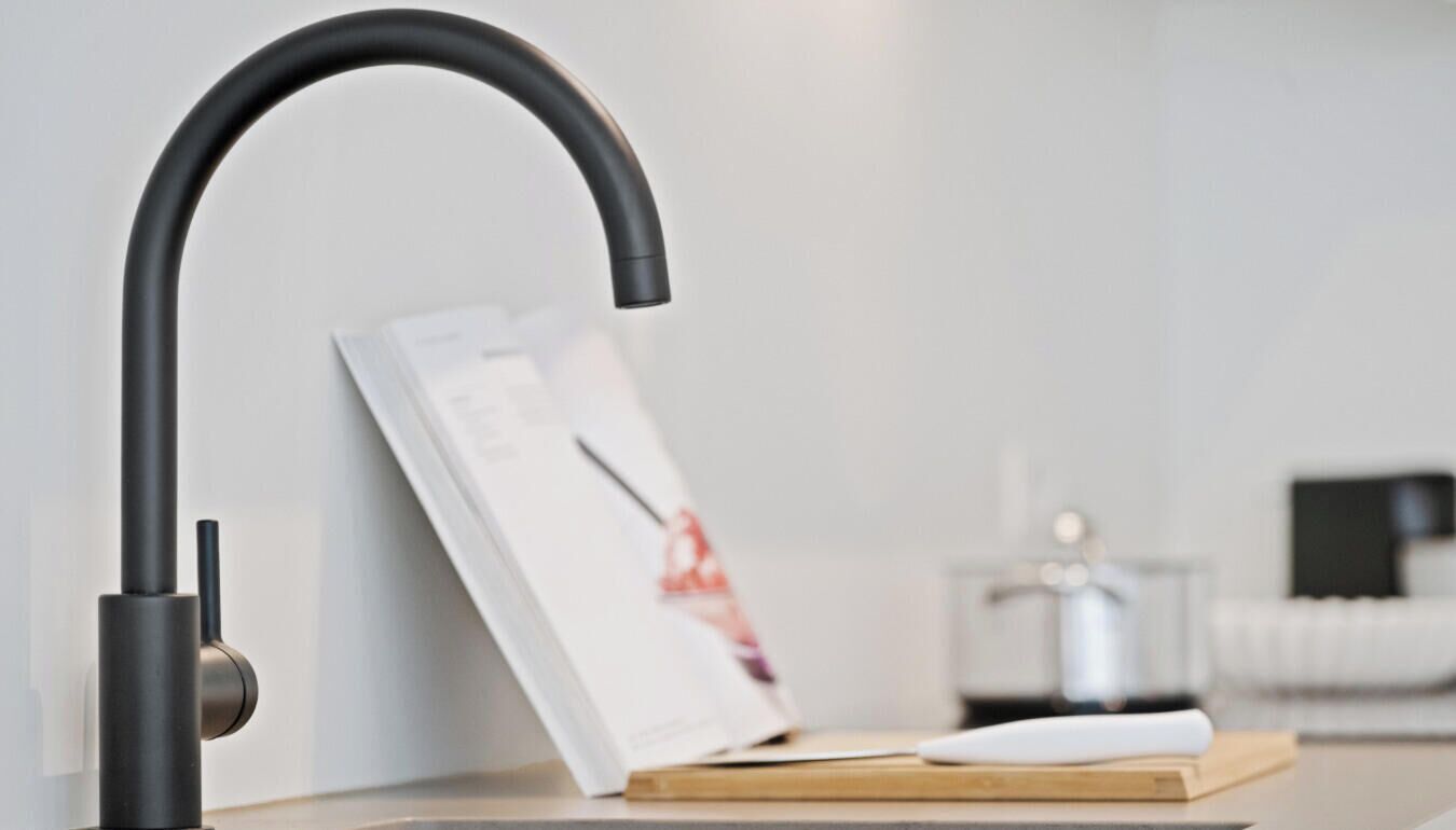 Une cuisine moderne avec un robinet noir élégant, une planche à découper en bois et un plan de travail blanc.