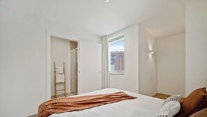 Ein Schlafzimmer mit Bett, Fenster, Tür und Handtuchhalter.