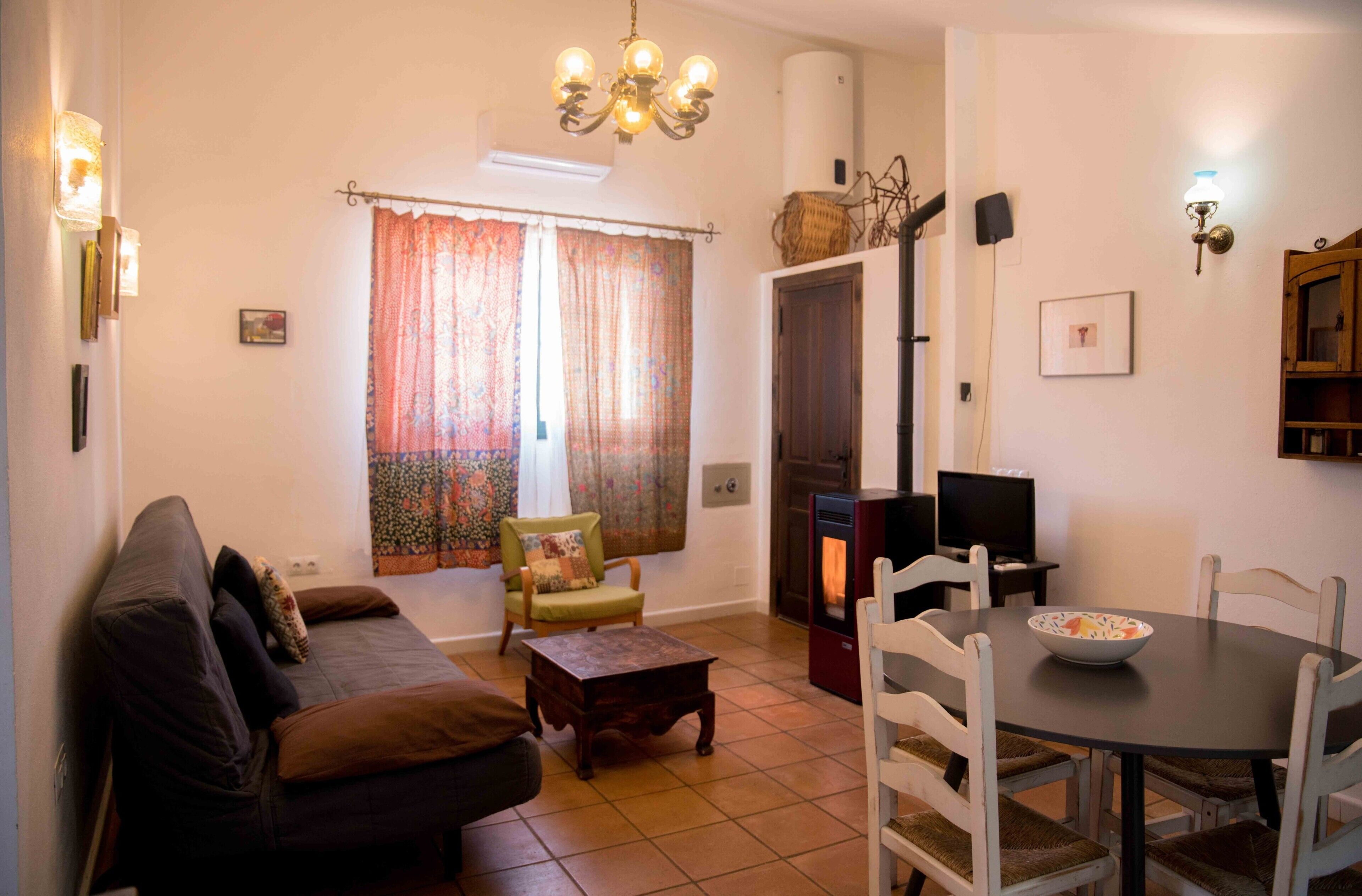 A living room with a sofa, a dining table, a chair, a fireplace, and a television.