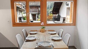 A dining table set for six with a view of a traditional wooden building and a balcony with chairs. - Charming apartment in an authentic village (Anniviers)