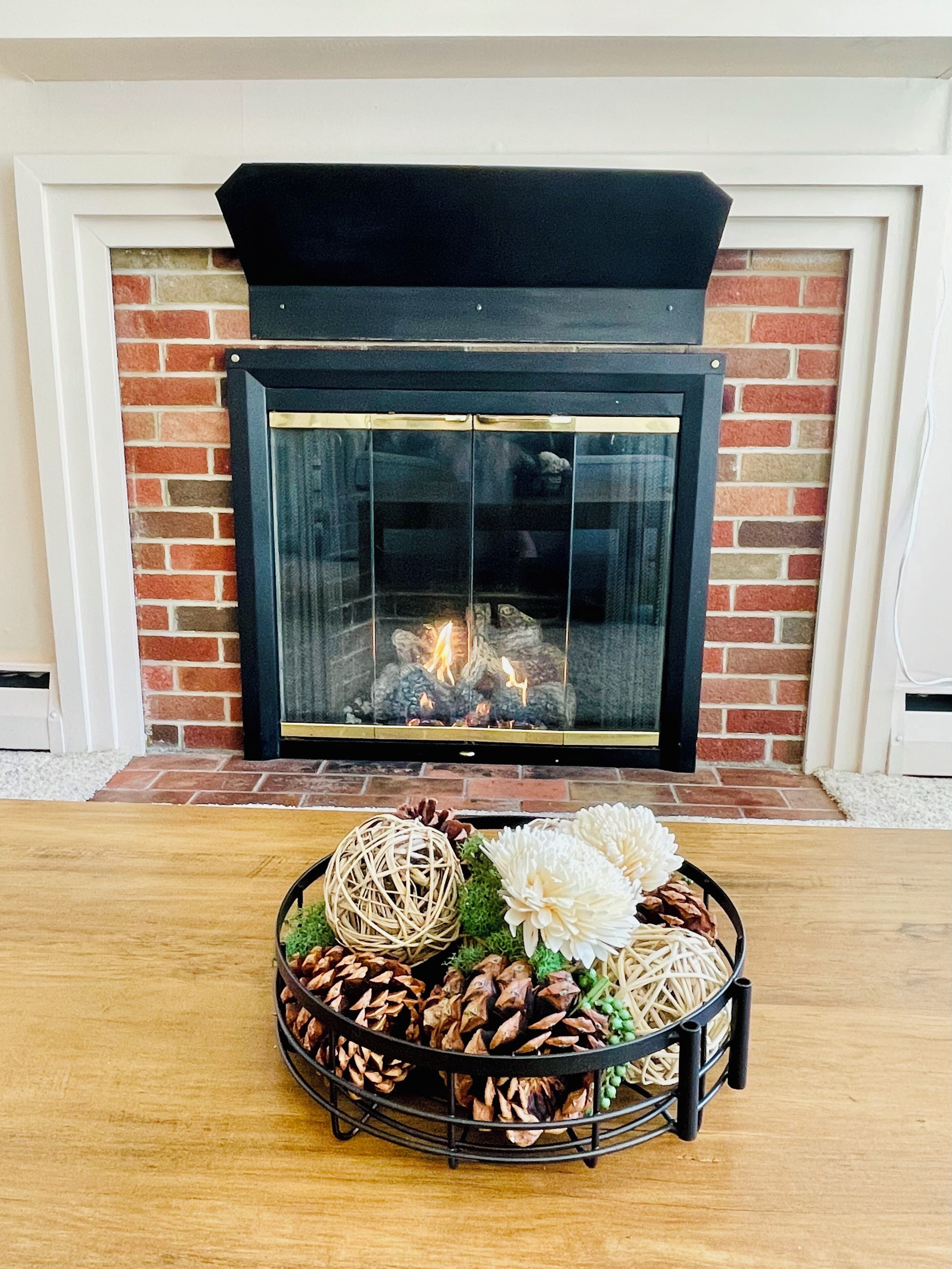 A fireplace with a brick wall, a table with decorative items, and a white door.