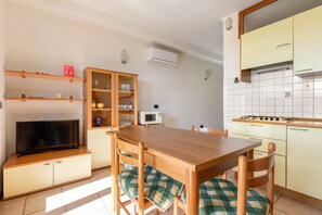 A compact kitchen with a wooden table, chairs, a microwave, and a gas stove. - Residence Le Magnolie 51 by Wonderful Italy (Sirmione)