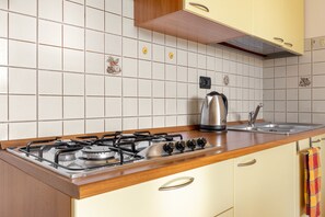 A kitchen with a gas stove, a kettle, and a sink. - Residence Le Magnolie 51 by Wonderful Italy (Sirmione)