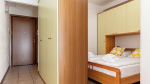 Ein Zimmer mit einem hölzernen Bett, einem Kleiderschrank und einer Tür.