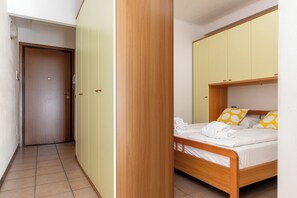 Um quarto com uma cama de madeira, um guarda-roupa e uma porta.