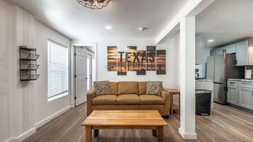 A modern living room with a wooden coffee table, a brown sofa, and a wall-mounted light fixture.