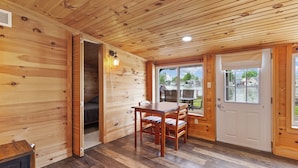L’intérieur d’une cabane en bois comprend un coin repas, une porte donnant sur l’extérieur et une fenêtre visible.