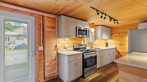 Une cuisine avec des murs en bois, une cuisinière, un four, un four à micro-ondes et des placards.
