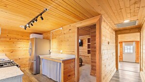 L’intérieur d’une cabane en bois comprend une cuisine, un réfrigérateur, une cuisinière et un coin repas.
