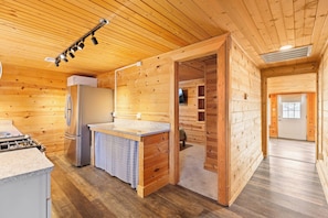 Ein Holzblockhaus-Interieur mit einer Küche, einem Kühlschrank, einem Herd und einem Essbereich.