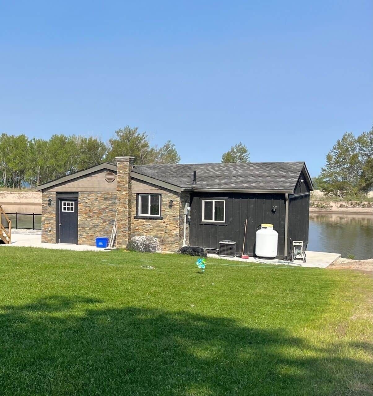 A house with a stone exterior, a garage, and a dock by a lake.