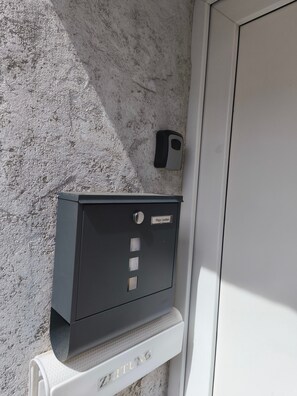 A metal safe with a keypad and a nameplate, mounted on a textured wall next to a door.
