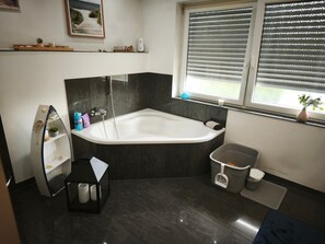 A modern bathroom with a freestanding bathtub, a vanity with a mirror, and a window with blinds. - Quiet Room with Private WC in Mönchengladbach (Mönchengladbach)