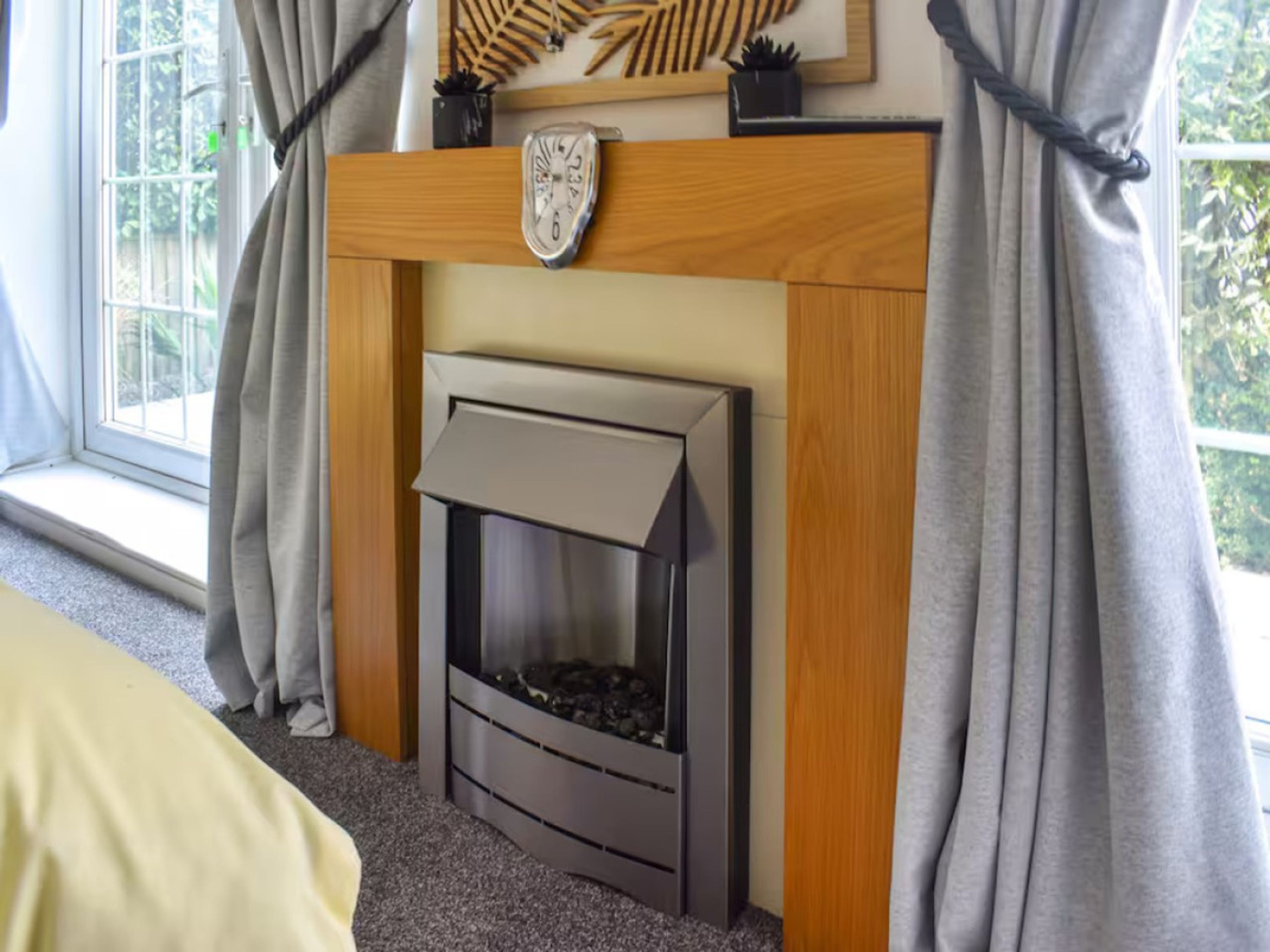 A room with a fireplace, a window with curtains, and a bed.