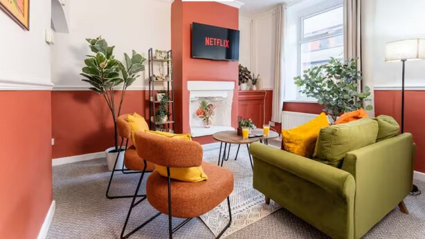 A living room with a sofa, chairs, a coffee table, a fireplace, and a TV mounted on the wall. - Spacious 2BR Family Home in Brierfield Near Burnley and Skipton (Burnley)