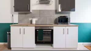 A kitchen with white cabinets, a microwave, and an oven. - Spacious 2BR Family Home in Brierfield Near Burnley and Skipton (Burnley)