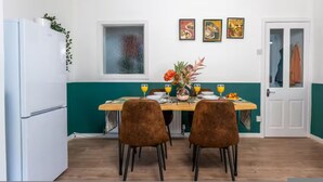 A dining area with a table set for two, a refrigerator, a window, and artwork on the wall. - Spacious 2BR Family Home in Brierfield Near Burnley and Skipton (Burnley)