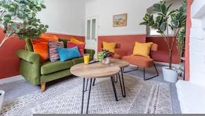 A room with a green sofa, a round wooden table, and a red accent wall. - Spacious 2BR Family Home in Brierfield Near Burnley and Skipton (Burnley)