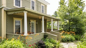 A two-story house with a porch, a front door, and a number '284' on the door. - Heritage home with spa, EV charger and walkable village (Potton)