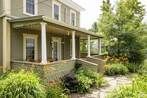 A two-story house with a porch, a front door, and a number '284' on the door. - Heritage home with spa, EV charger and walkable village (Potton)